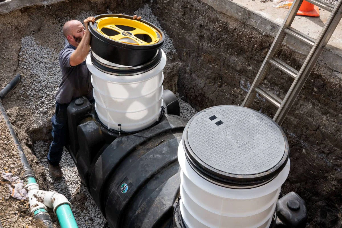 Schier Lifetime Guaranteed Grease Interceptor — Outdoor Installation Plumber installing a Schier grease interceptor in an underground excavation site